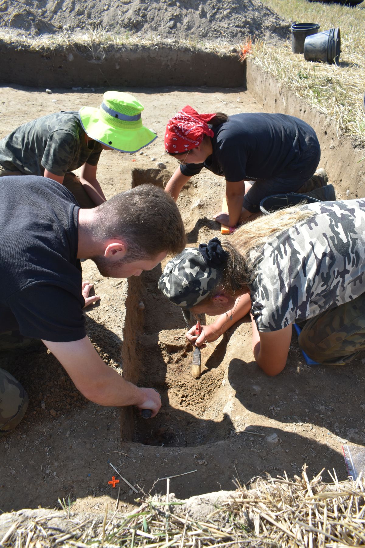 Studenci archeologii ostrożnie odsłaniają pozostałości wyposażenia żołnierza.