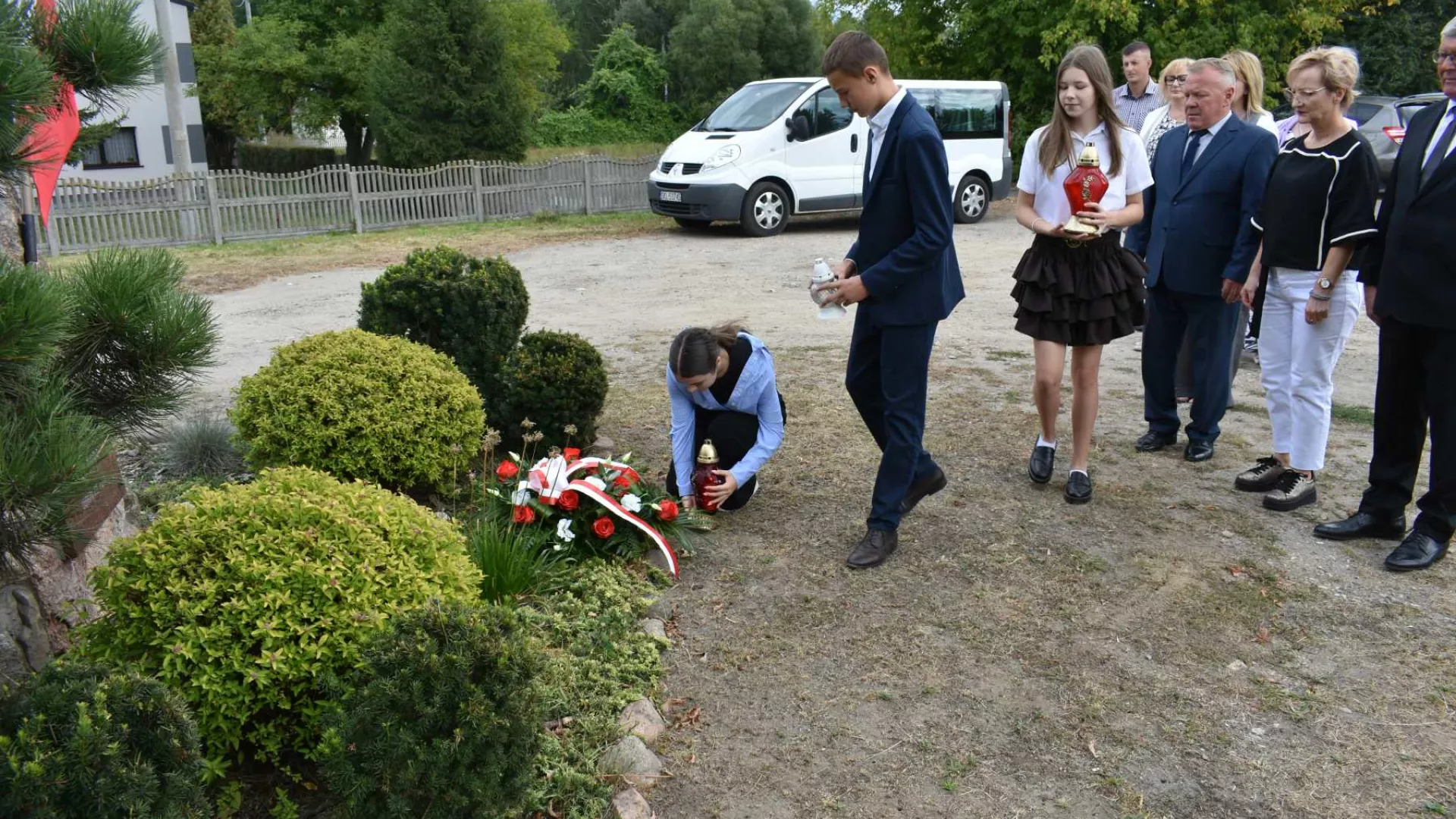 Uczniowie składają znicze pod obeliskiem koło mostu w Dankowie.
