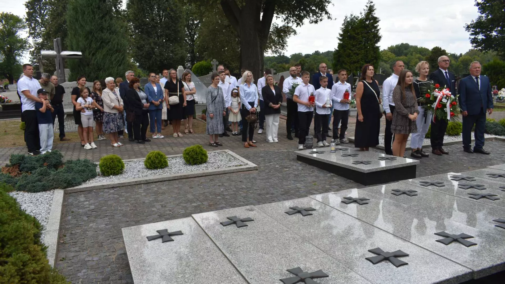 Uczestnicy ceremonii złożenia kwiatów przed mogiłą żołnierską w Parzymiechach.