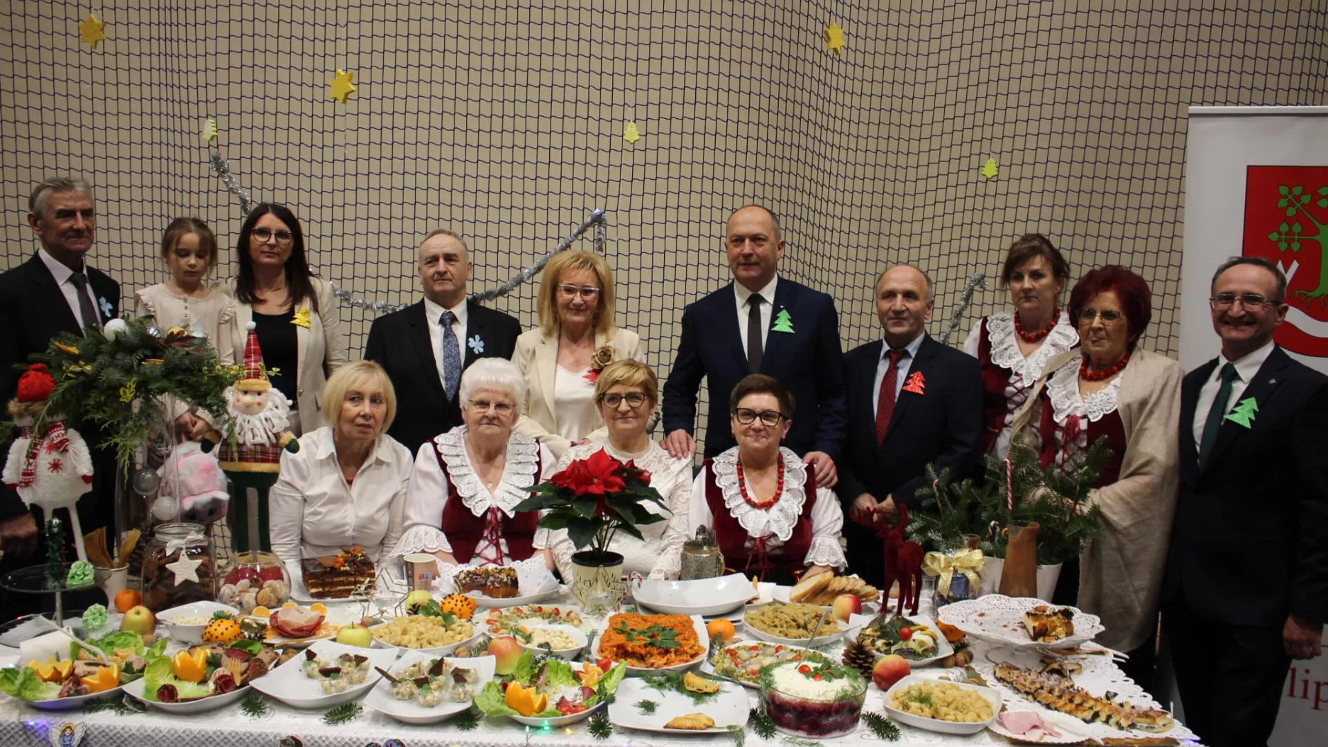 Wspólna fotografia KGW Lipie i honorowych gości prezentacji przy stole bożonarodzeniowym