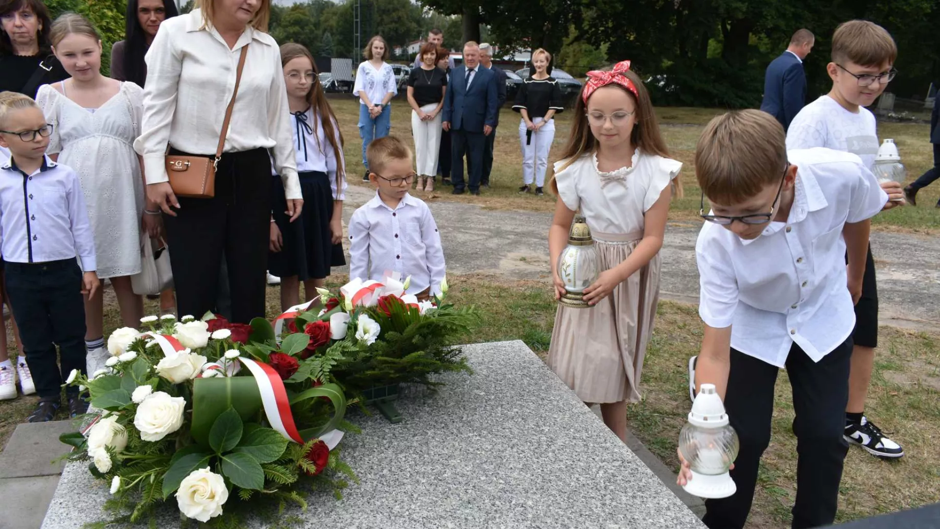 Dzieci składają znicze na grobie ofiary niemieckiej zbrodni wojennej.