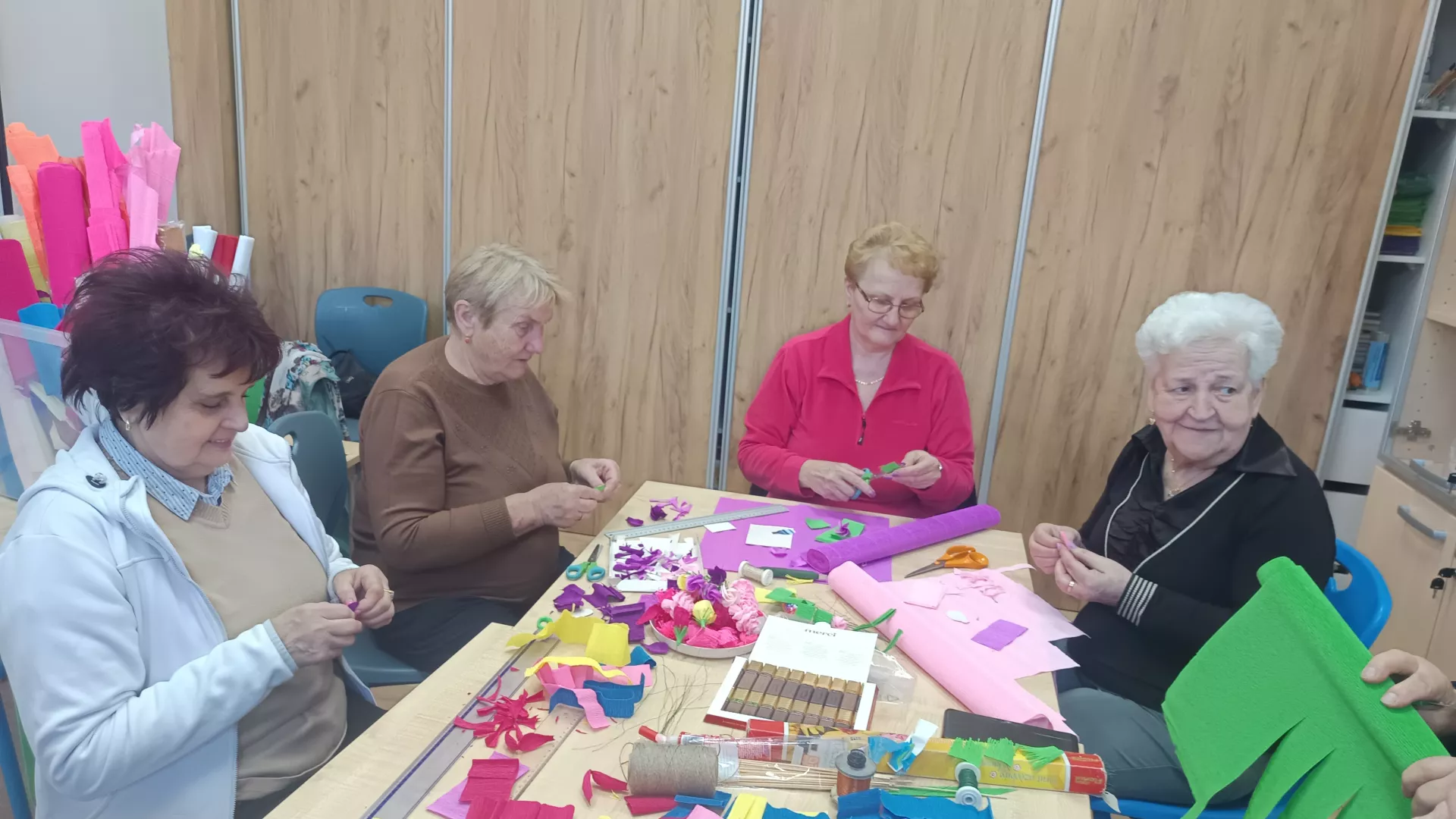 Uczestnicy zajęć podczas przygotowywania palm wielkanocnych podczas zajęć z animatorem w klubie seniora w Lipiu.