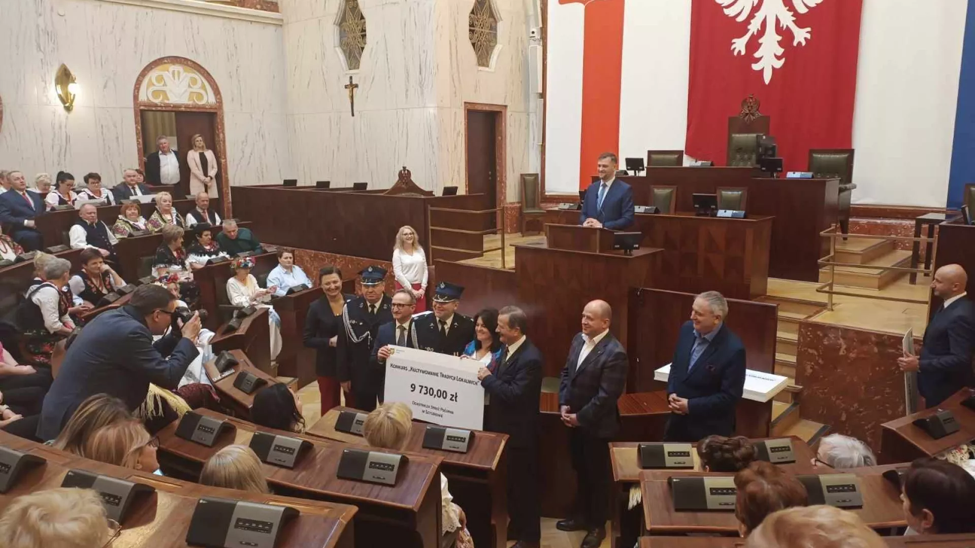 Przedstawiciele OSP Szyszków i KGW Szyszków odbierają symboliczny czek dotacji na zadanie publiczne.