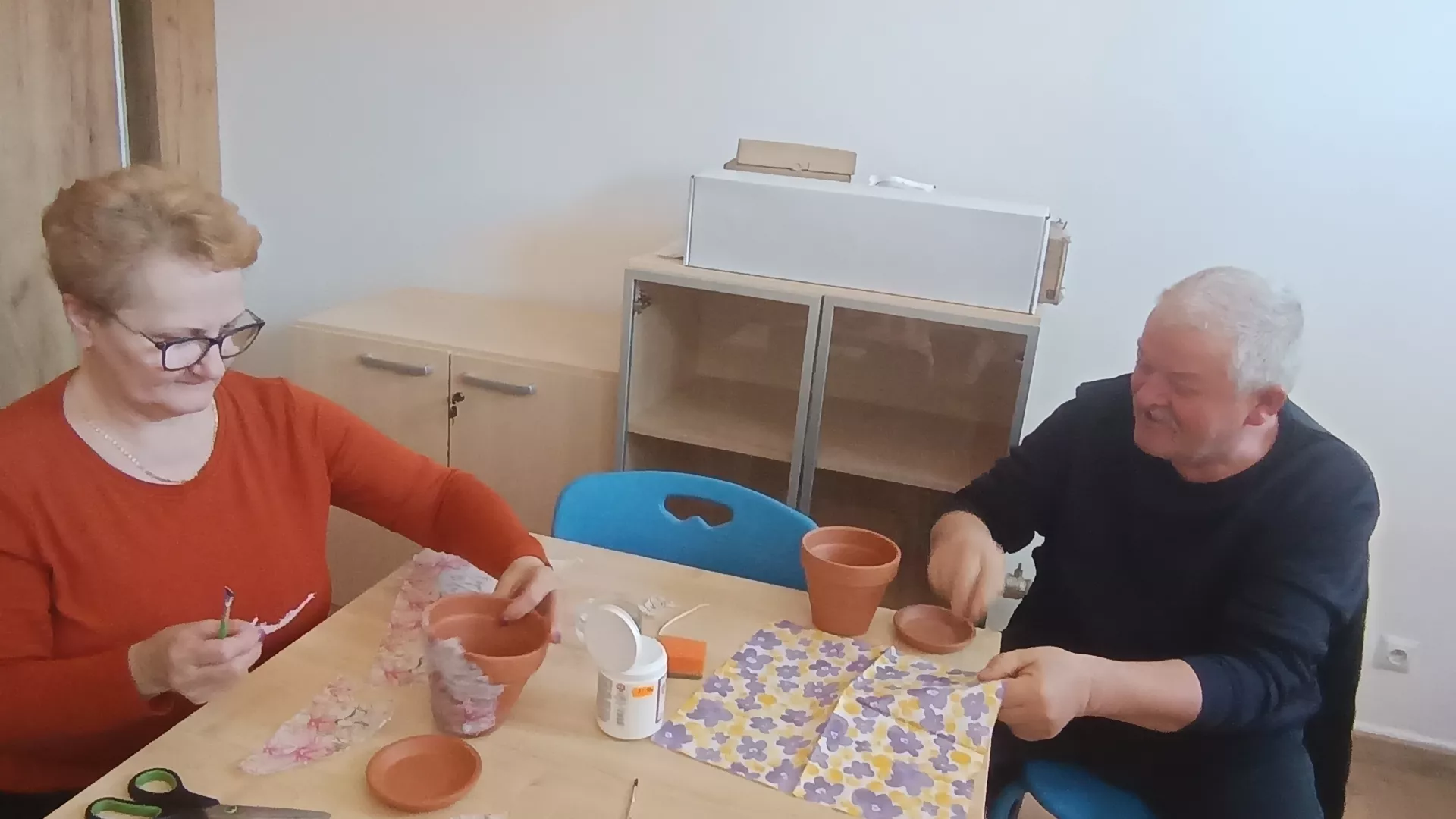 Uczestnicy zajęć podczas dekorowanie doniczek metodą decoupage w czasie zajęć z animatorem w klubie seniora w Lipiu.