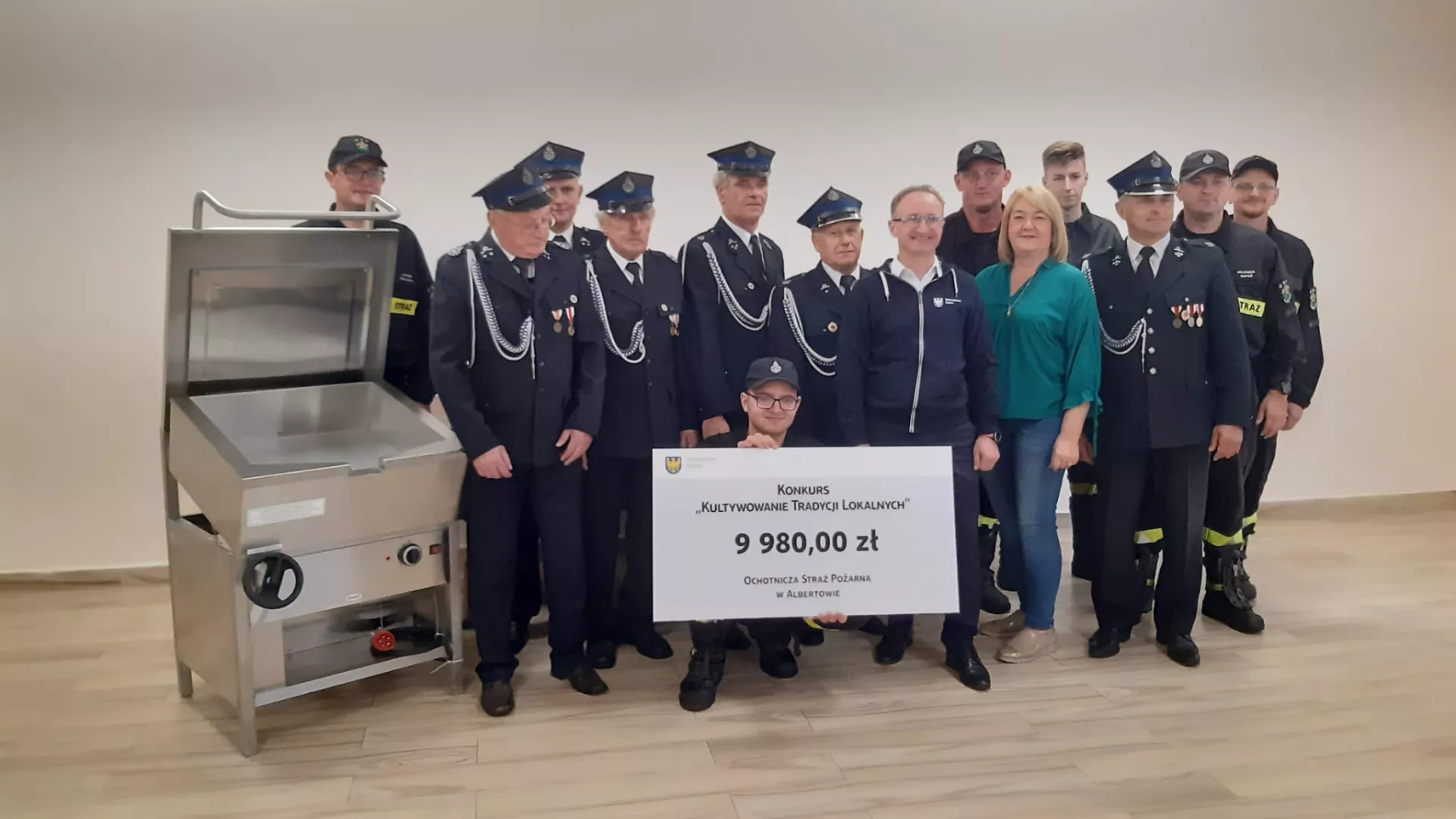 Grupa strażaków z OSP Albertów z symbolicznym czekiem w asyście członka Zarządu Województwa Śląskiego Grzegorza Boskiego.