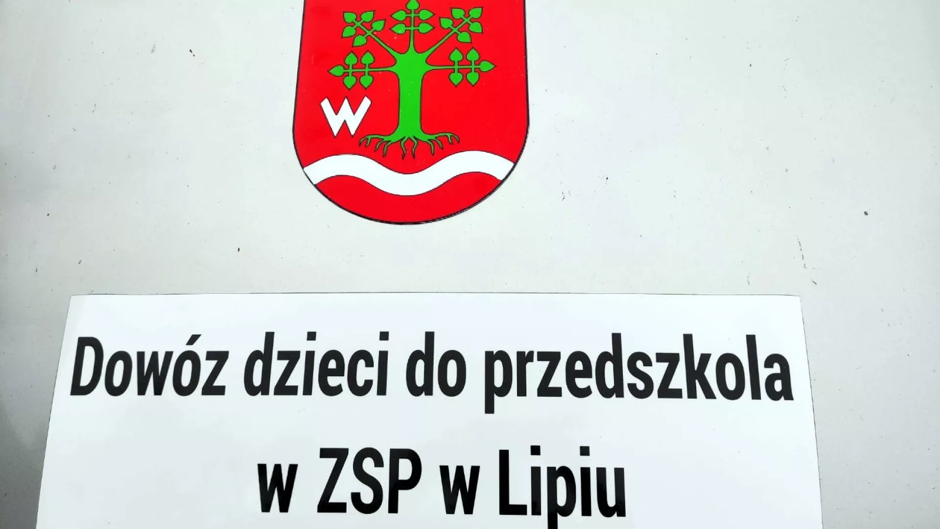 Herb gminy i napis: „Dowóz dzieci do przedszkola w ZSP w Lipiu”.