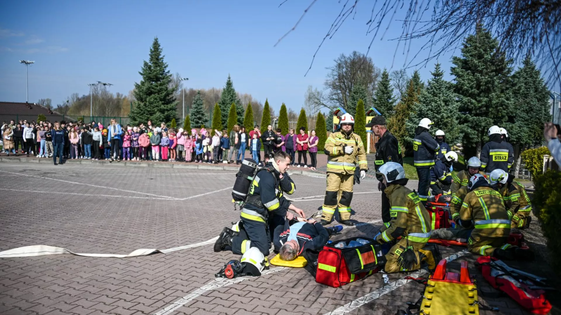 Strażacy udzielający pierwszej pomocy osobom poszkodowanym oraz ewakuowani uczniowie, nauczyciele i pracownicy obsługi w ZS-P Lipie
