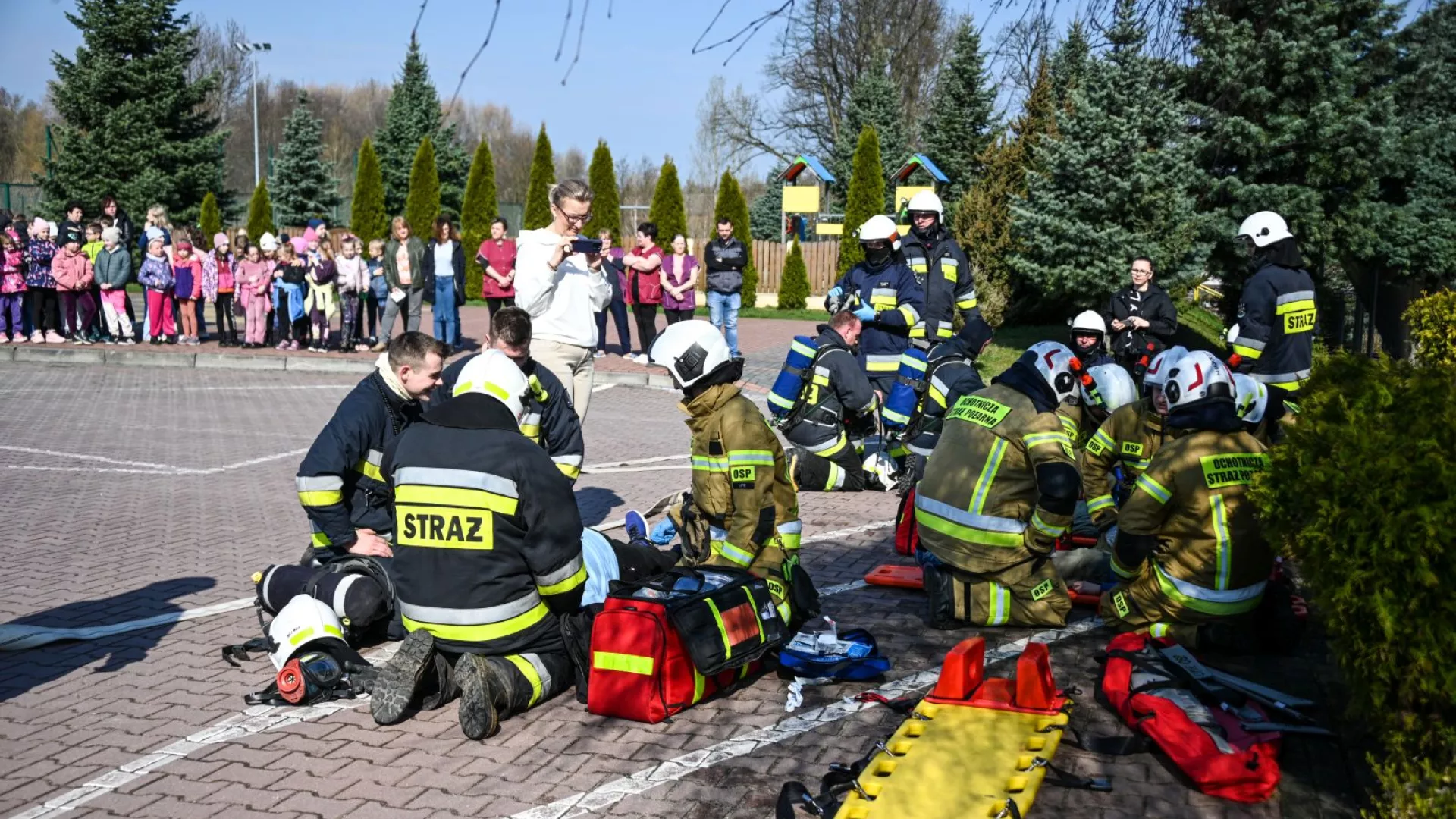Strażacy udzielający pierwszej pomocy osobom poszkodowanym oraz ewakuowani uczniowie, nauczyciele i pracownicy obsługi w ZS-P Lipie