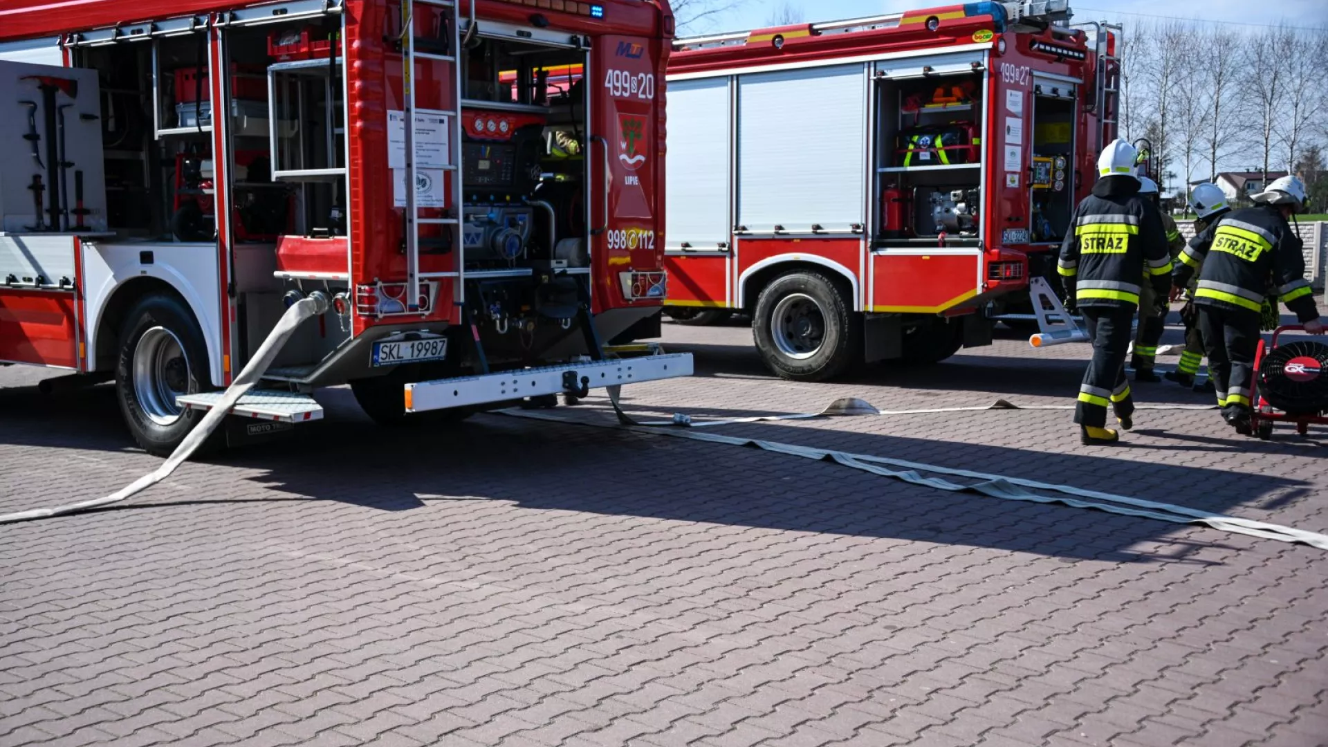 Strażacy na tle samochodów strażackich