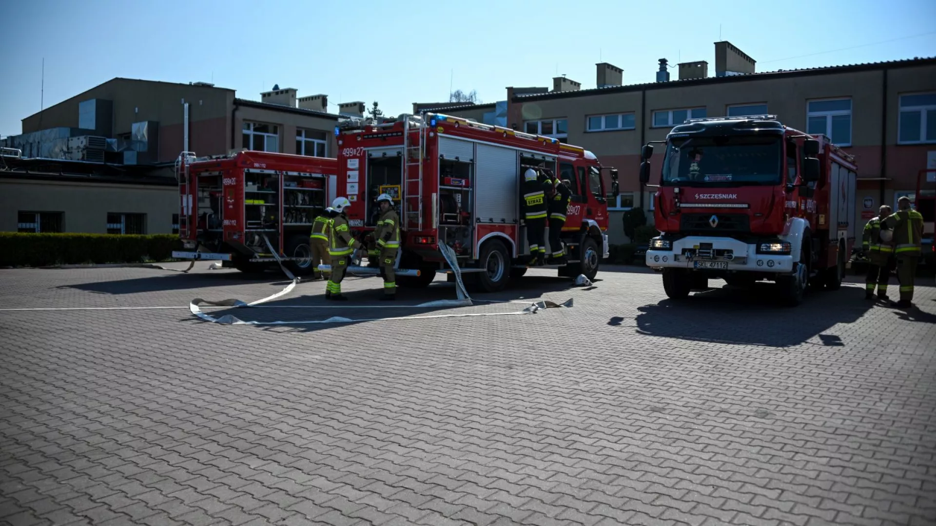 Strażacy na tle samochodów strażackich