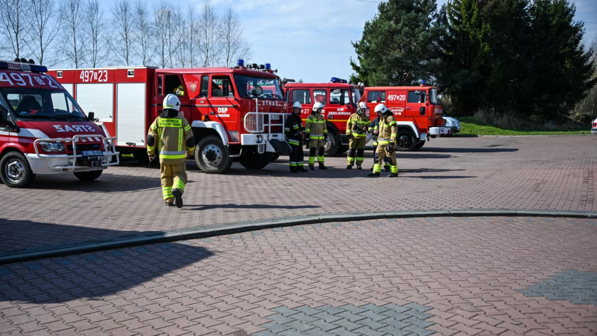 Strażacy na tle samochodów strażackich