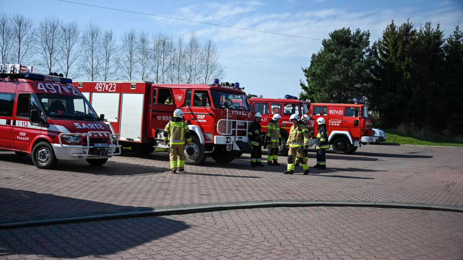 Strażacy na tle samochodów strażackich