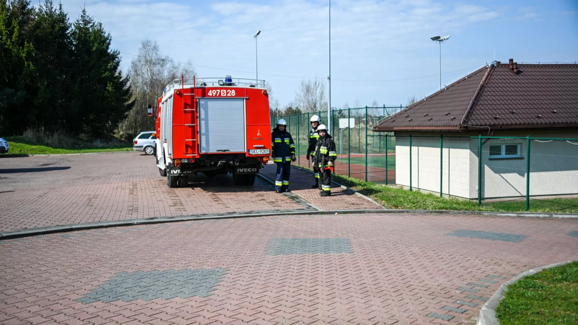 Strażacy na tle samochodów strażackich