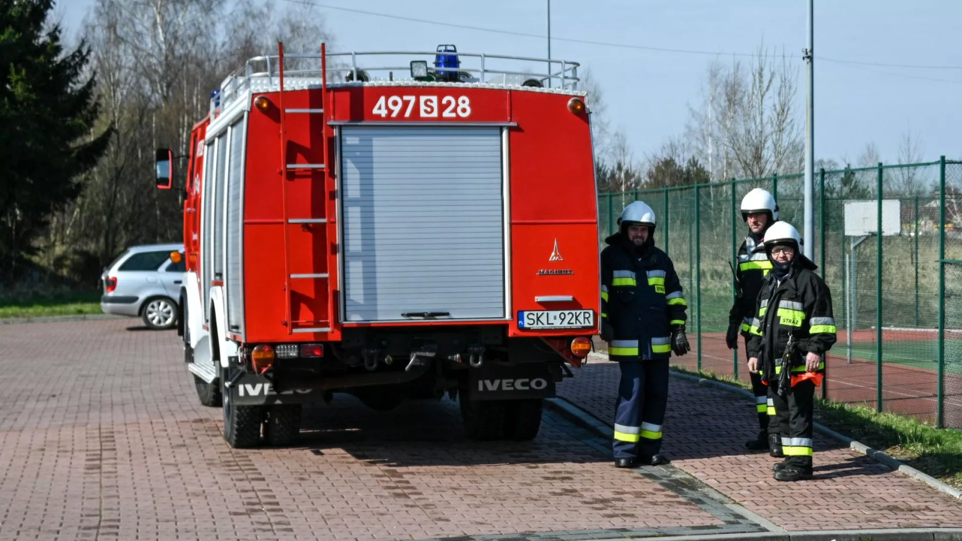 Strażacy na tle samochodów strażackich
