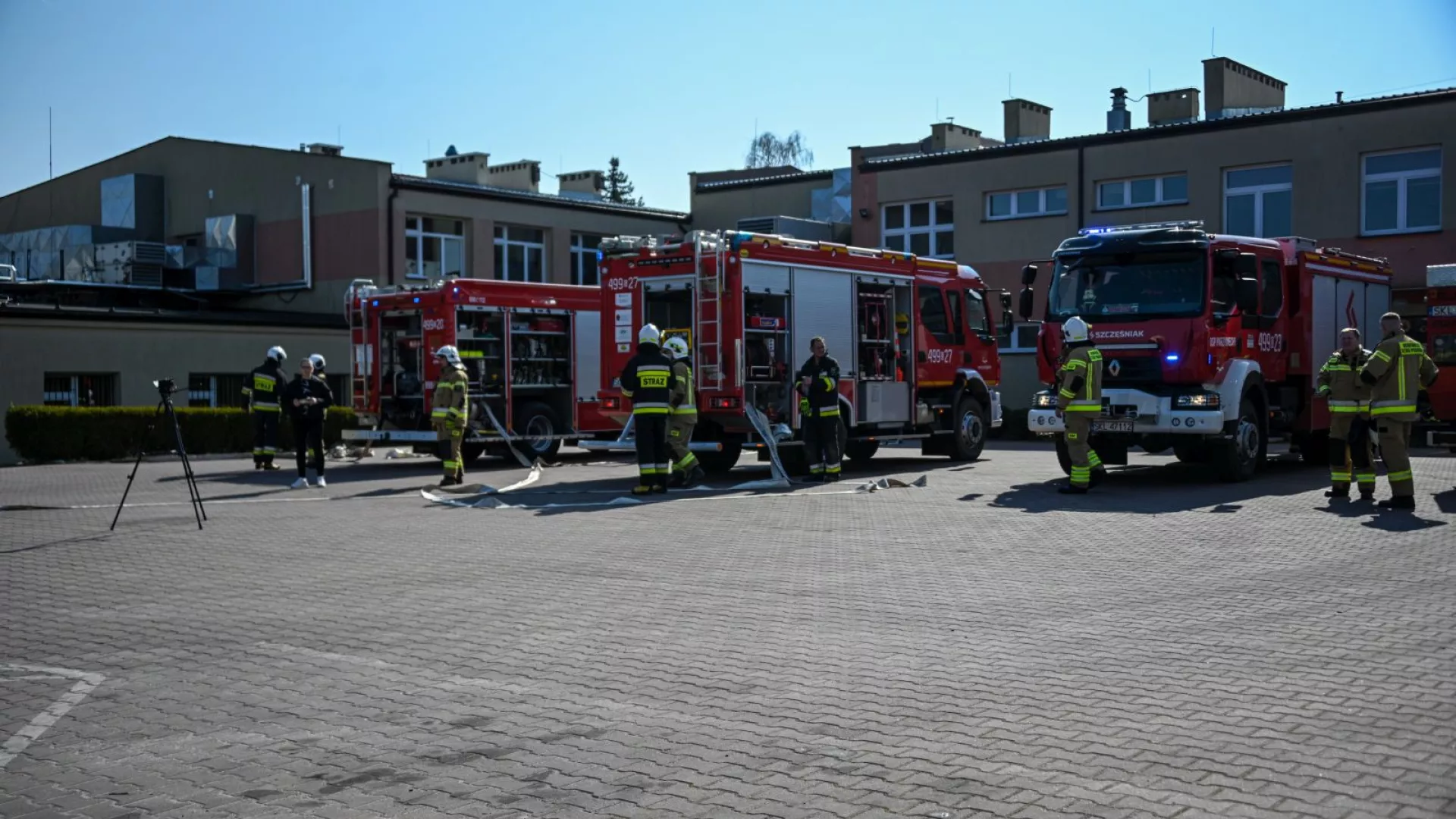 Strażacy na tle samochodów strażackich