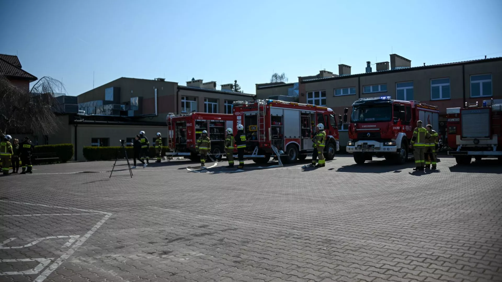 Strażacy na tle samochodów strażackich