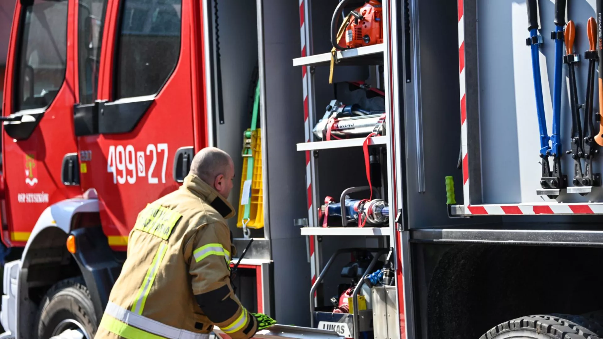 Strażacy na tle samochodów strażackich