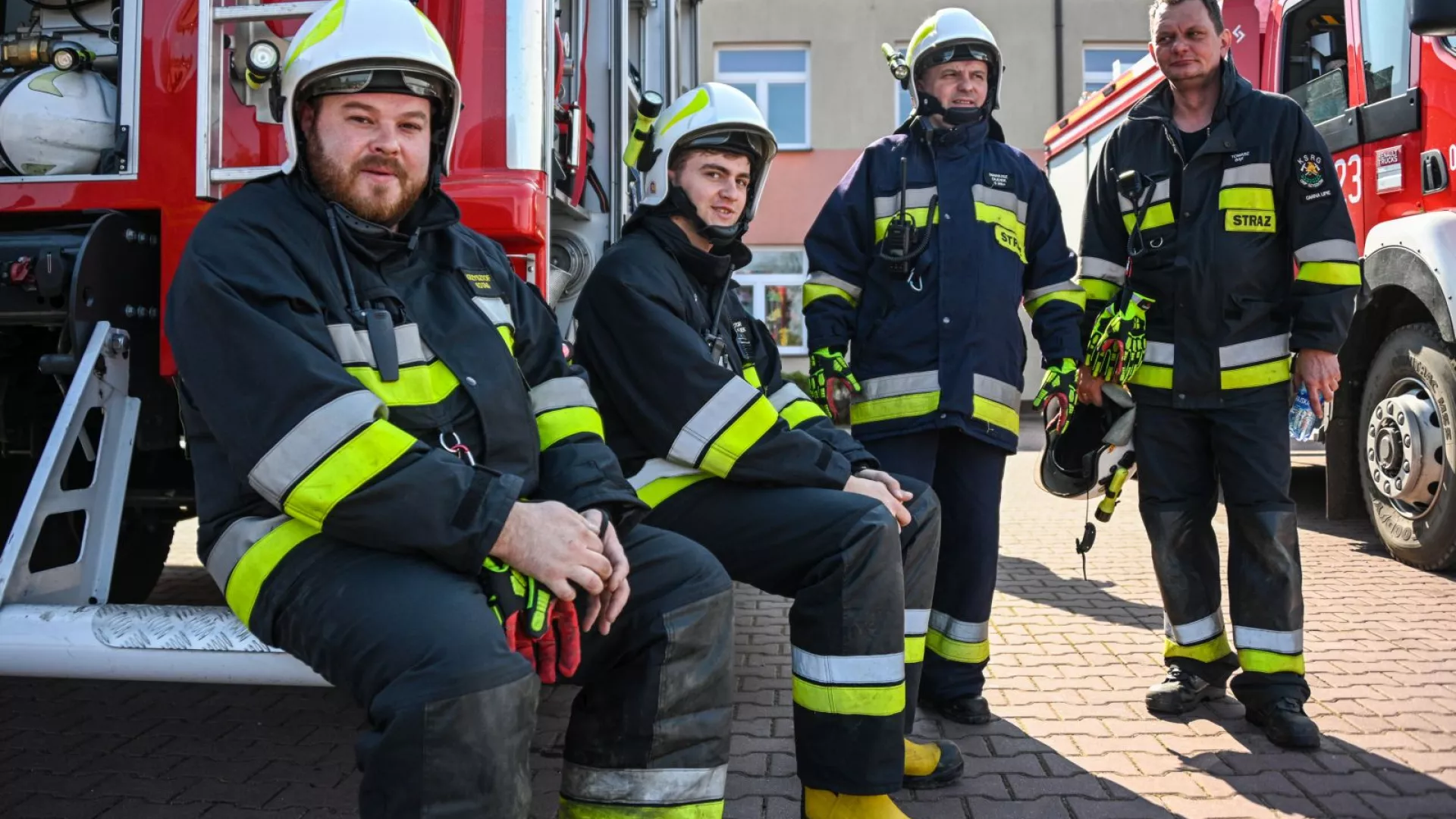 Strażacy na tle samochodów strażackich
