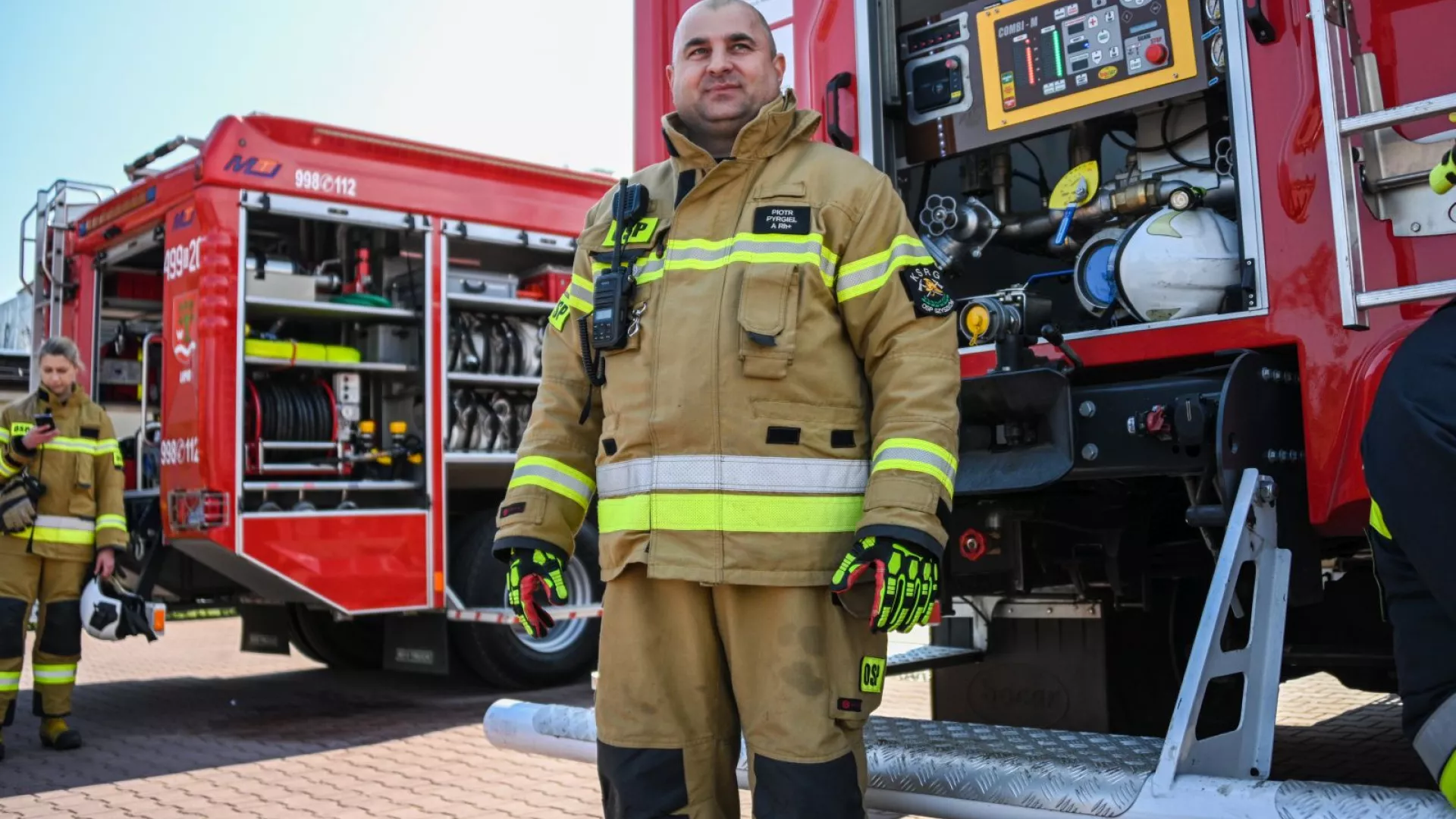 Strażacy na tle samochodów strażackich