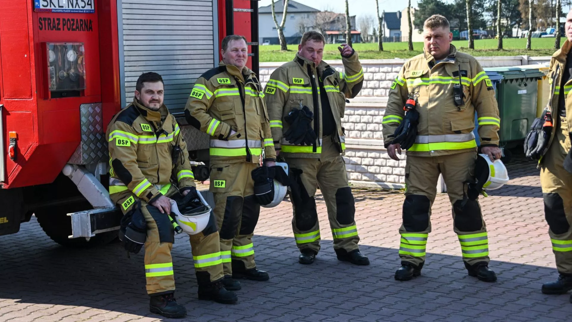 Strażacy na tle samochodów strażackich