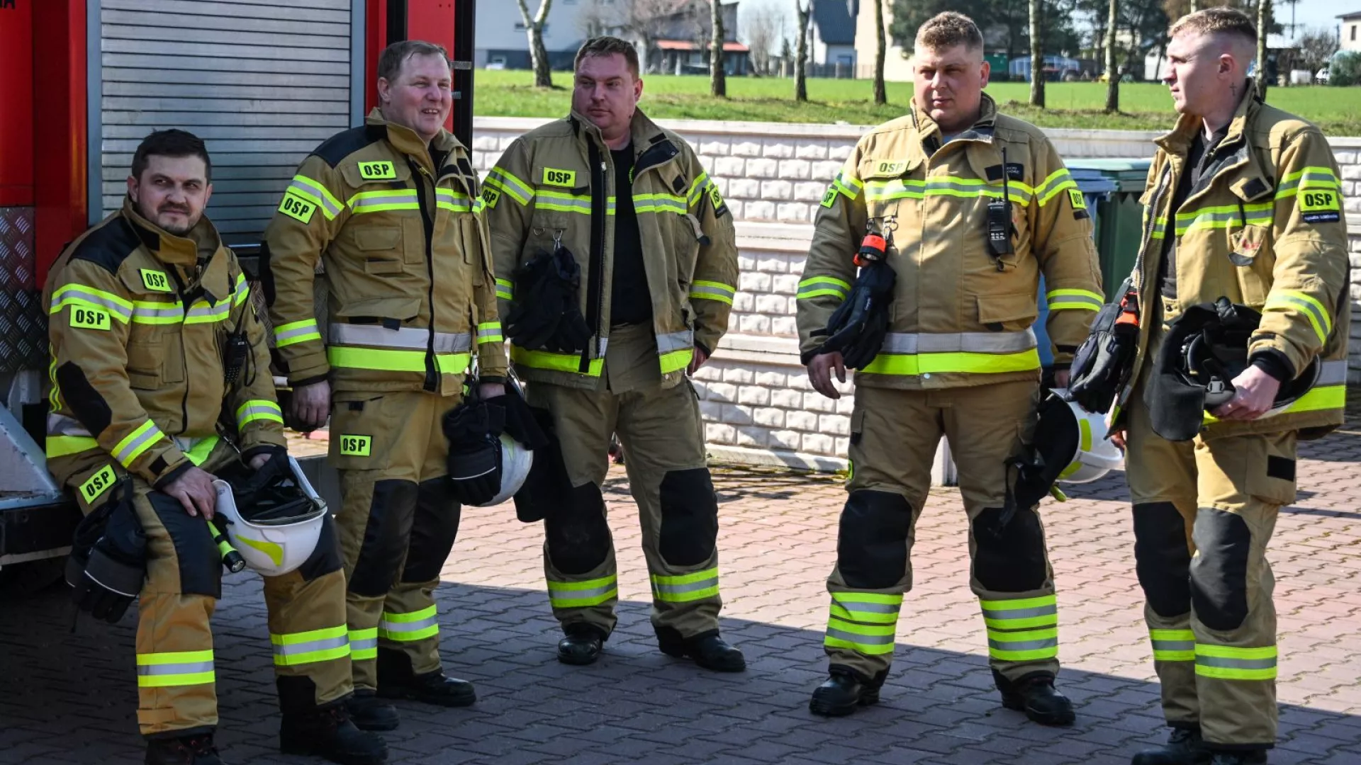 Strażacy na tle samochodów strażackich