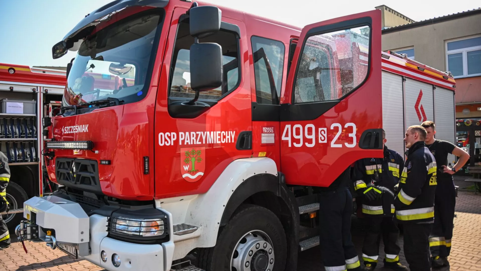 Strażacy na tle samochodów strażackich