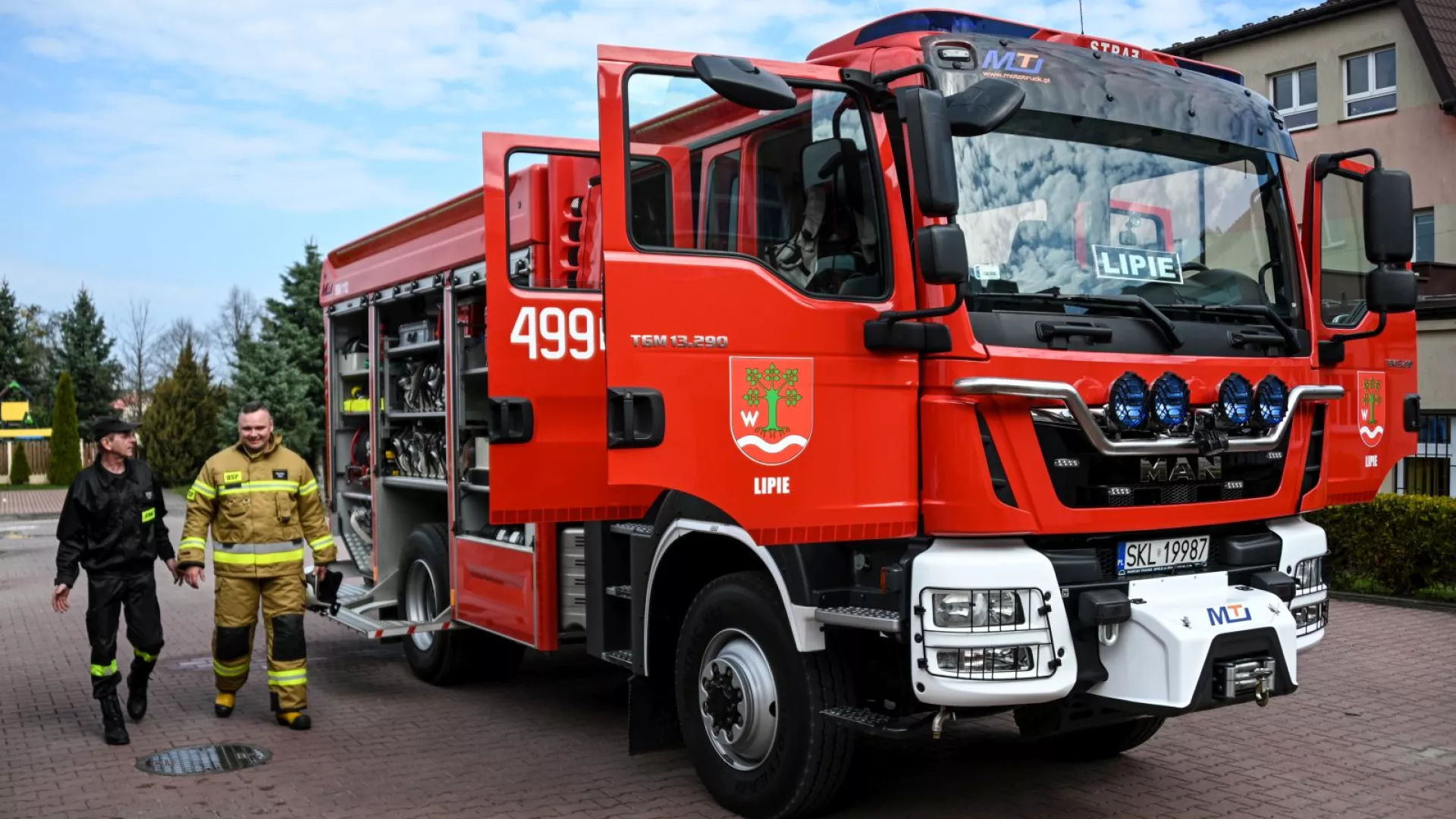 Strażacy na tle samochodów strażackich