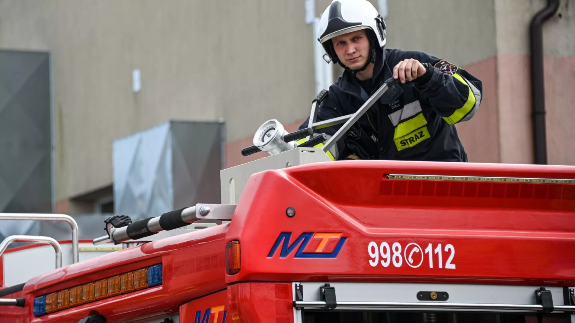 Strażak na dachu samochodu strażackiego
