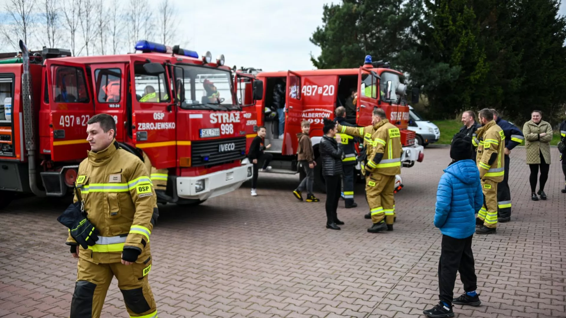 Strażacy na tle samochodów strażackich