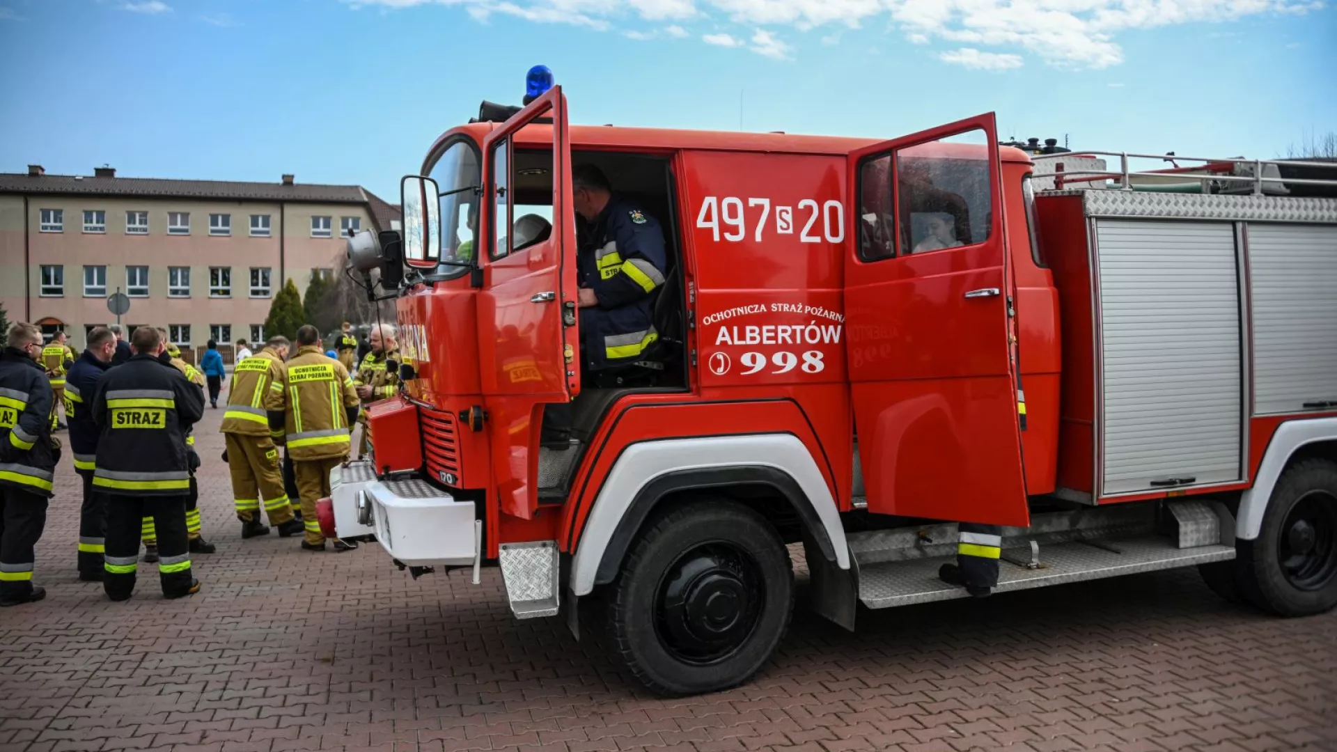 Strażacy na tle samochodów strażackich