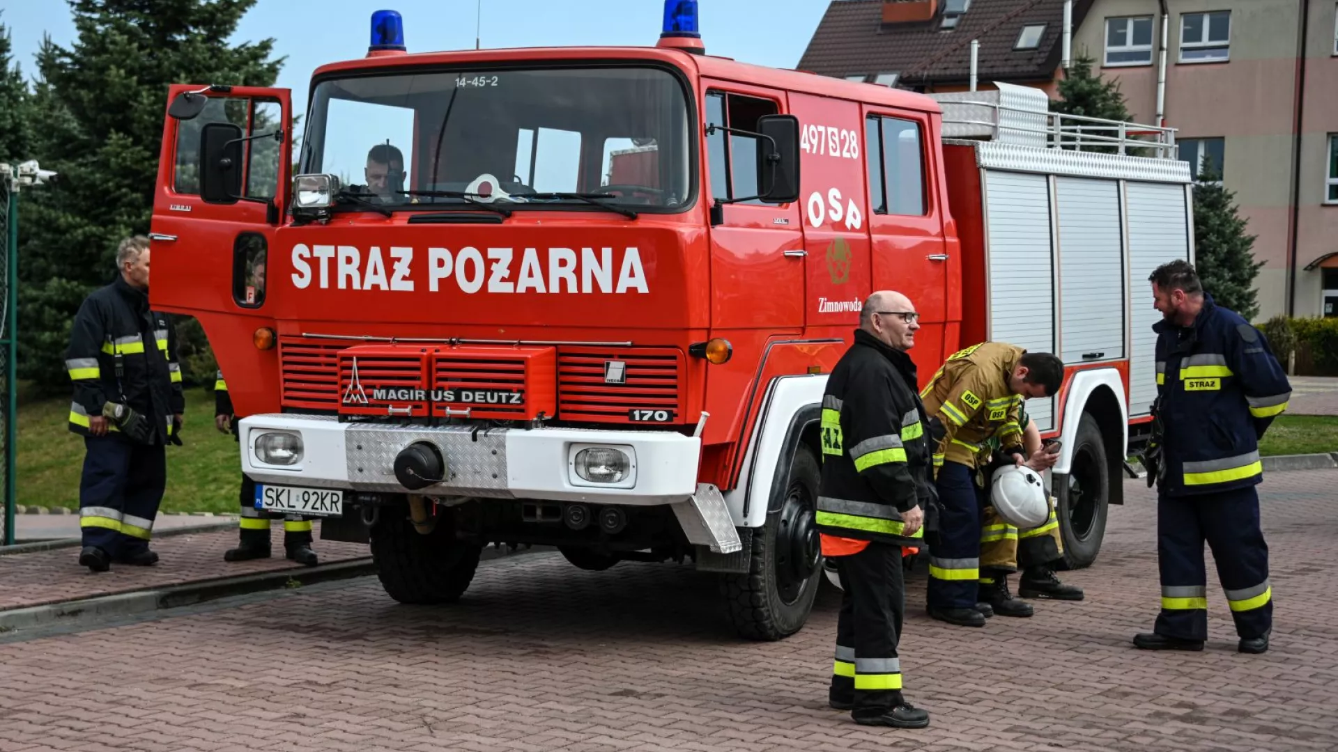 Strażacy na tle samochodów strażackich