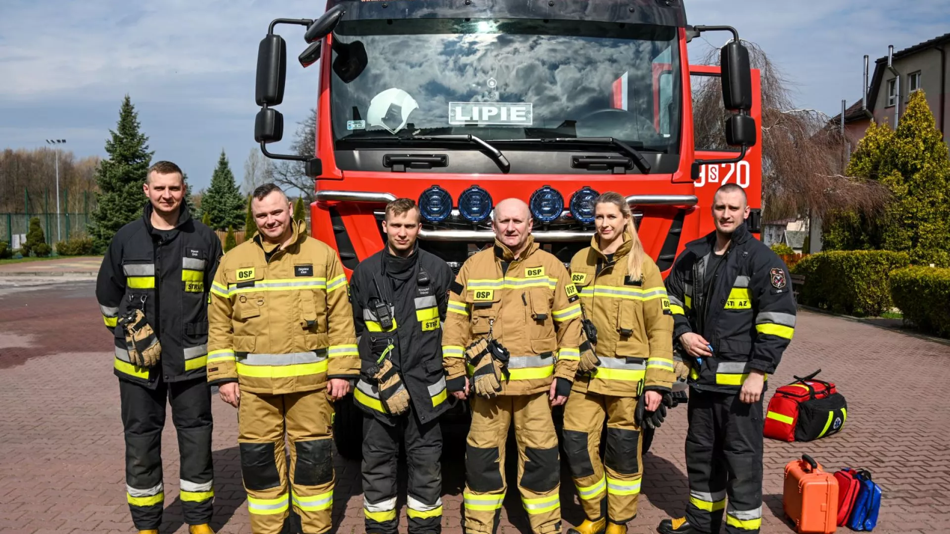 Strażacy OSP Lipie na tle samochodu strażackiego