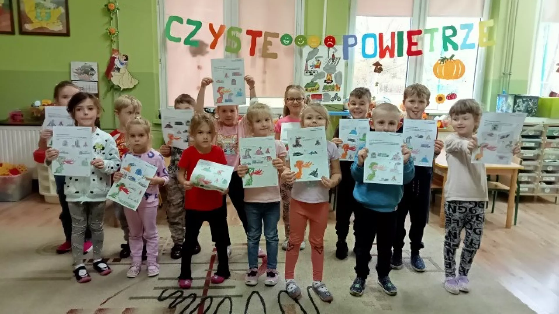 Grupa dzieci prezentuje w klasie swoje prace plastyczne.