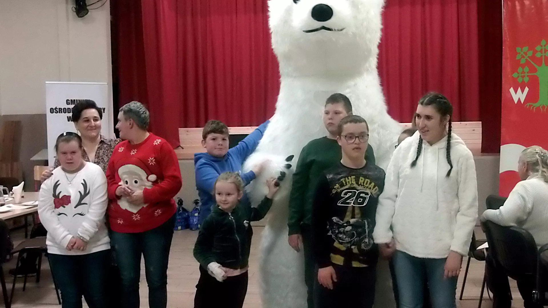 Zabawa uczestników mikołajek z dużym białym misiem.