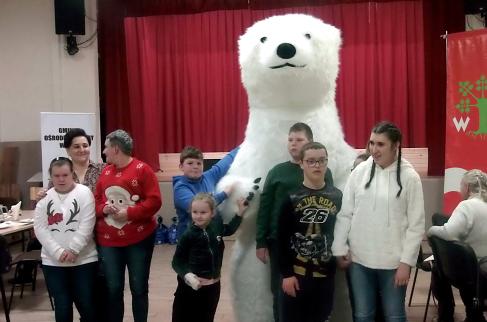 Zabawa uczestników mikołajek z dużym białym misiem.